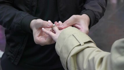 Capturing a romantic outdoor proposal with a closeup of the engagement ring being placed on the finger, symbolizing the start of a new journey and a special moment for the couple