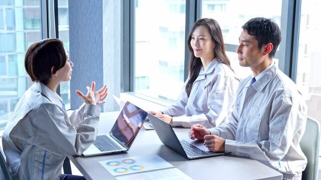 パソコンを使い会議をする作業着を着た男女