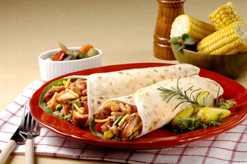 빨간색 접시위에 닭고기 요리가 들어가있는 부리또와 야채.