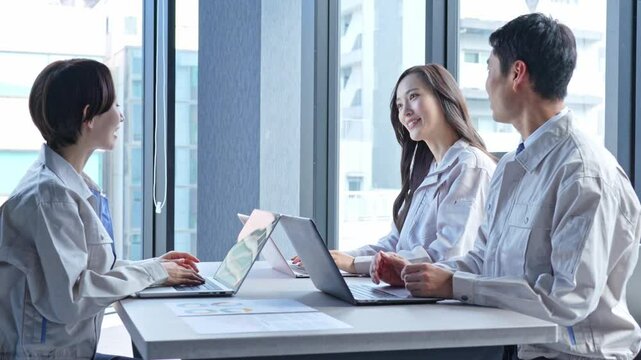 パソコンを使い会議をする作業着を着た男女