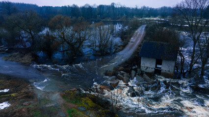 river flood ecology disaster early spring season in March with destroyed road and building and dam depressive aerial country side suburban dirty view