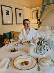 A man is enjoying a luxurious breakfast in an elegant hotel room