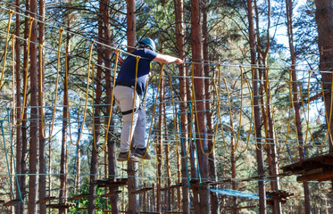 A man is walking across a rope bridge in the woods