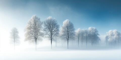 A snowy forest in winter is enveloped in mist, showcasing trees blanketed in white and a serene blue sky above, creating a tranquil winter landscape.