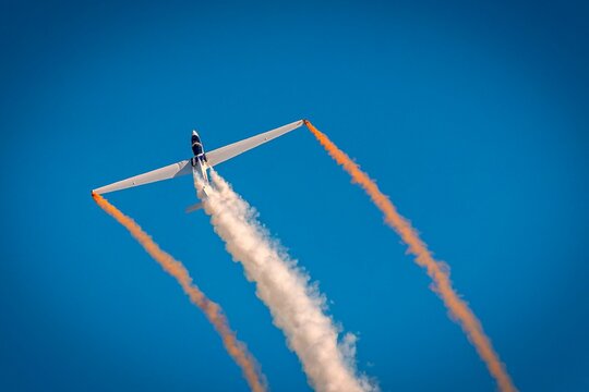 Aerobatic glider with vibrant smoke trails.