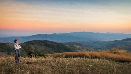 Woman traveler looking at the sunset over mountain view at Doi Chang , Chiangrai, Thailand