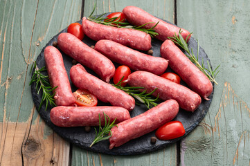 Raw beef sausages with rosemary and tomatoes photography . Top view