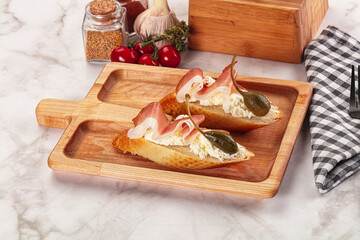 Bruschetta with jamon and caper berries