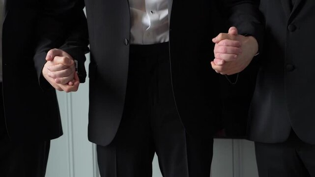 A united gesture of three business professionals in suits symbolizes teamwork and collaboration in a corporate setting. This reflects commitment, cooperation, and a strong sense of corporate unity