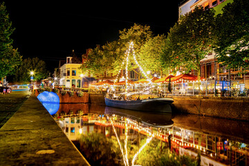Nightlife in Leeuwarden in the Nieuwestad with illuminated gastronomy boats at night, Friesland,...