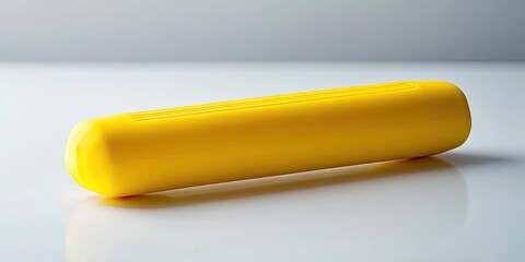 A yellow hand grip is positioned on a white surface. The yellow hand gripper lies on top of the clean white backdrop, showcasing its vibrant color against the contrast.
