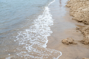 Shallow waves washing onto sandy beach shore.