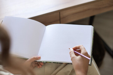 Closeup of Person Holding Blank Open Notebook with Pencil