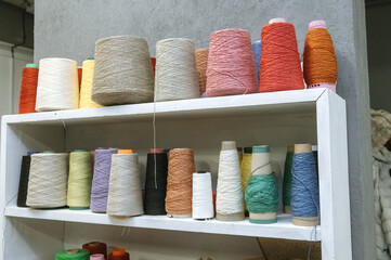Colorful yarn spools in various sizes on shelves for crafting and textile art projects