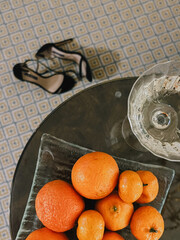 Elegant Shoes and Fresh Citrus Fruits neatly arranged on a Patterned Floor