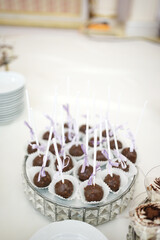 Sweet chocolate candies with filling on a stick on a buffet table.