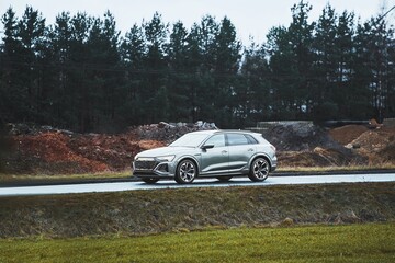 Fototapeta premium SUV on rainy countryside drive with green and dirt hills
