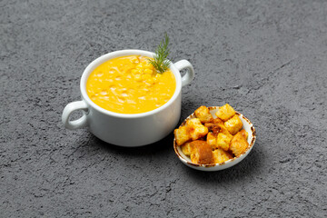 Cheese soup with corn and bread croutons. On a gray background.