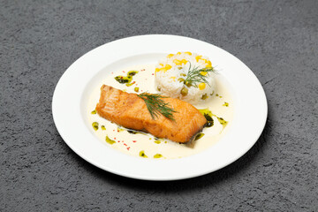 Salmon steak with boiled rice on a plate. On a gray background. Photo for the menu.