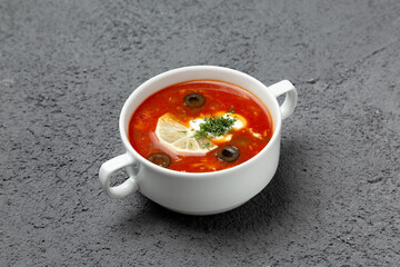 Solyanka soup with olives and lemon. On a gray background. Photo for the menu.