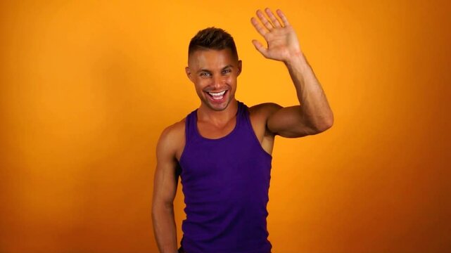 Summer mood. Young athletic man posing in studio on orange background.