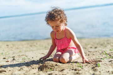 Girl playing on a sandy beach on summer vacation. A child is building a sand castle on the sea.