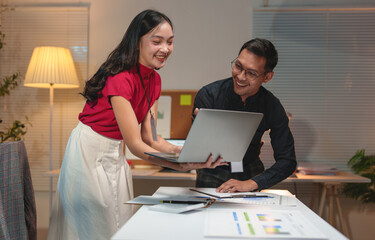 Obraz premium Young business team Young Asian woman discussing real estate project on tablet, laptop sitting at desk in office Two colleagues of professional business people working together teamwork concept.