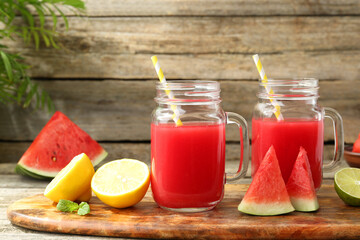 Tasty watermelon drink in mason jars and fresh fruits on wooden table