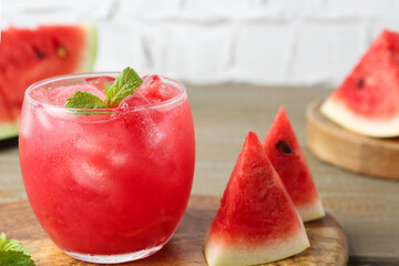 Tasty watermelon drink in glass, mint and fresh fruit on wooden table, closeup