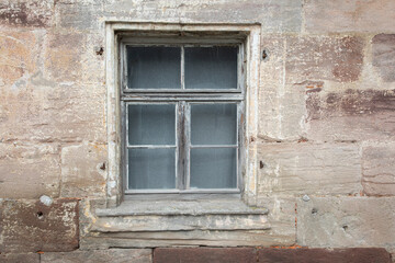 old window with shutters in sand stone house