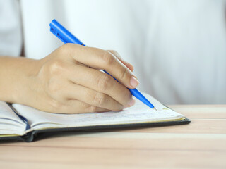 Hand holding pen writing on note paper. Finance business concept. Copy space.