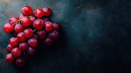 Top view of a cluster of red grapes on a dark surface