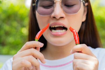 Close-up picture of a Asian girl eating chili over nature background.