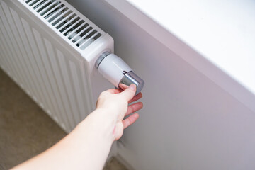 Woman regulates temperature at home with the heating knob on room battery