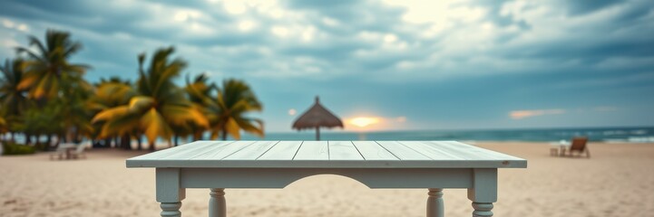 Obraz premium A white wooden table sits on the sandy beach with a palm tree and a sunset in the background