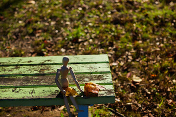 秋の公園のベンチに座る可愛いマネキン人形の様子