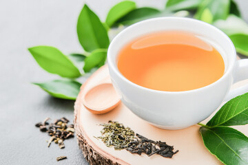 A close-up of dried tea leaves, fresh mint, and a steaming tea cup, symbolizing natural refreshment. 