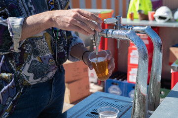 Un camarero sirviendo una caña de cerveza de grifo en una barra al aire libre.