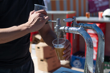 Un camarero sirviendo una caña de cerveza de grifo en una barra al aire libre.