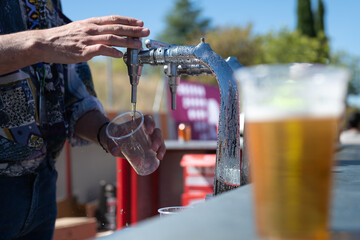 Un camarero sirviendo una caña de cerveza de grifo en una barra al aire libre.