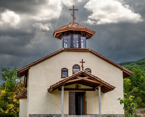 A small chapel on the background of mountains with clouds.