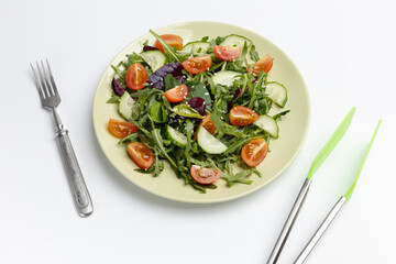 Vegetable salad of tomato, cucumber, greens on the plate.