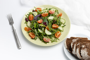 Vegetable salad of tomato, cucumber, greens on the plate.