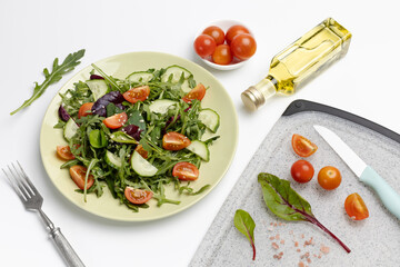 Vegetable salad of tomato, cucumber, greens on the plate with olive oil.