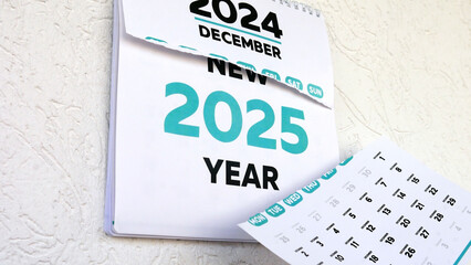 The falling torn page of a wall calendar and the following announcement of the New Year 2025 behind it