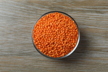 Red lentils in a bowl on wooden background 