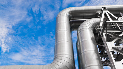 The photo shows pipeline lines against the backdrop of blue sky and clouds