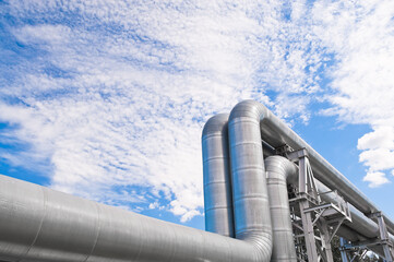 The photo shows pipeline lines against the backdrop of blue sky and clouds