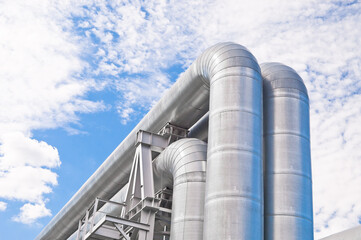 The photo shows pipeline lines against the backdrop of blue sky and clouds