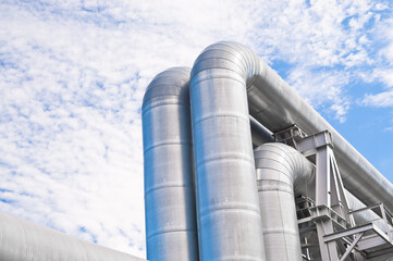 The photo shows pipeline lines against the backdrop of blue sky and clouds